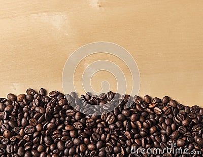 Spilled fresh coffee beans on blonde wooden table Stock Photo