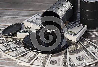 Spilled oil from a barrel to a dollar bill of money. Stock Photo