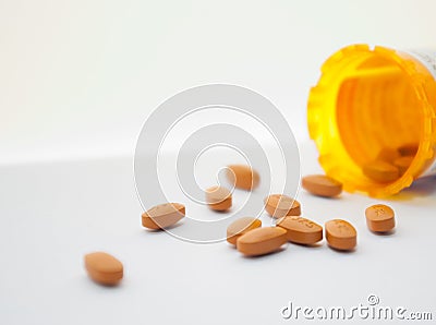 Spilled orange pills on white surface Stock Photo