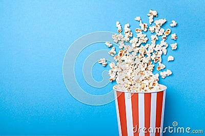 Spilled popcorn and paper bucket in red strip on blue background Stock Photo