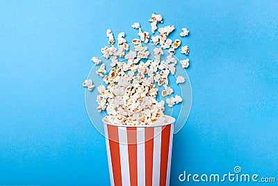 Spilled popcorn and paper bucket in red strip on blue. Copy space for text Stock Photo