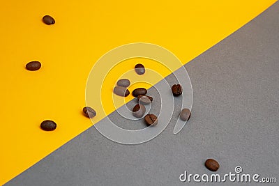 Spilled roasted brown coffee beans isolated on yellow background, close up with copy space Stock Photo