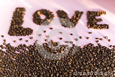 Spilled roasted coffee beans with a love inscription. Stock Photo