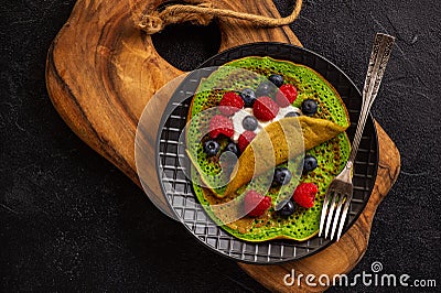 Spinach crepes with cheese , raspberries and blueberries. Stock Photo