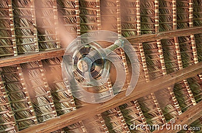 A spinning fan in the background of a wicker roof Stock Photo