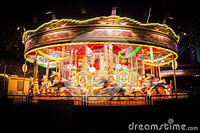 A spinning vintage carousel at night leaving colorful light trails Stock Photo