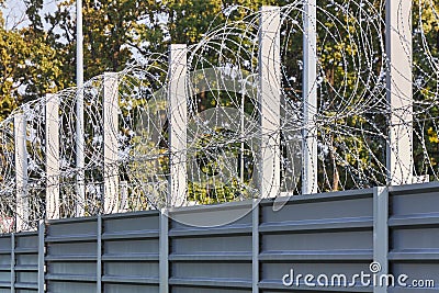 Spiral barbed wire on the fence protects against penetration Stock Photo