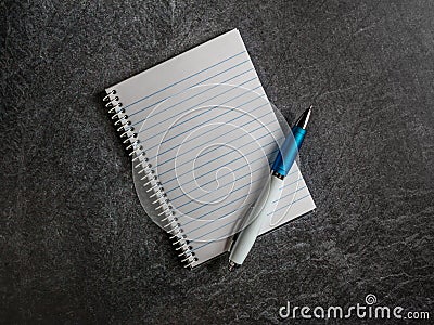 Spiral notebook with empty page and pen on a dark slate background copy space Stock Photo