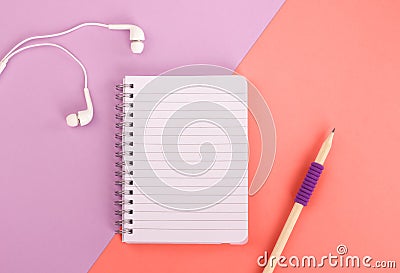 Spiral notepad and pencil on pastel purple and coral background. Stock Photo