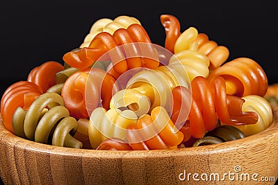 Spiral pasta trottole tricolore isolated in wooden bowl Stock Photo