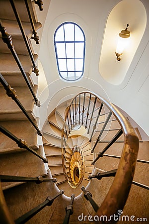 Spiral staircase in interior of historical house. Old architecture with stairs, window and space between floors Stock Photo