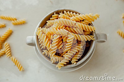 Spiral tortiglioni pasta in marble plate with two handles on light background. homemade pasta made from durum wheat. raw dish. Stock Photo