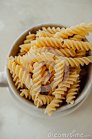Spiral tortiglioni pasta in marble plate with two handles on light background. homemade pasta made from durum wheat. raw dish. Stock Photo