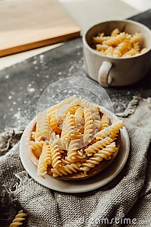 Spiral tortiglioni pasta in plate on dark table in flour with burlap cloth napkin. real life atmosphere. homemade pasta made from Stock Photo