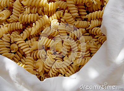 Spiral yellow pasta in a white fabric bag close up Stock Photo