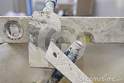 Spirit level with parts of other plastering tools on a metal plate under the plaster splashes Stock Photo