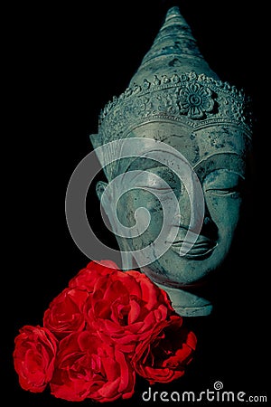 Spiritual love. Beautiful blue buddha head statue with red roses Stock Photo