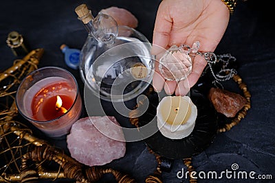 Spiritualistic Experience, esoteric table, female fortuneteller's hand holding and using glass ball crystal, candles burn, Stock Photo