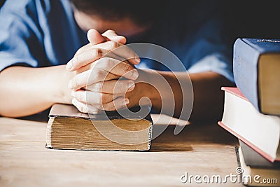 Spirituality and religion, Hands folded in prayer on a Holy Bible in church Stock Photo