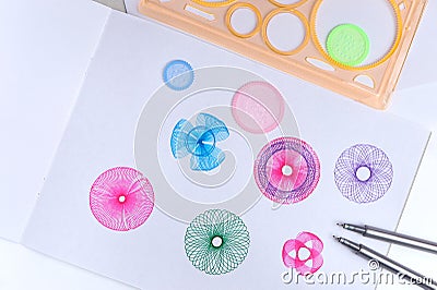 Spirograph ruler on white background. Drawing the spirograph pattern on paper. Stock Photo