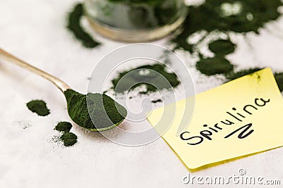 Spirulina green powder on single spoon with handwritten spirulina word Stock Photo