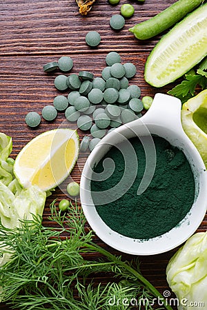 Spirulina powder around green fresh vegetables. served at woodentable Stock Photo