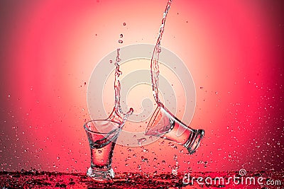 Splash in a flying wineglass with water or vodka on a red gradient background Stock Photo