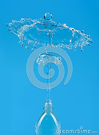 A splash of water with drops escaping from a PET bottle on a blue background. The concept of pure bottled water Stock Photo