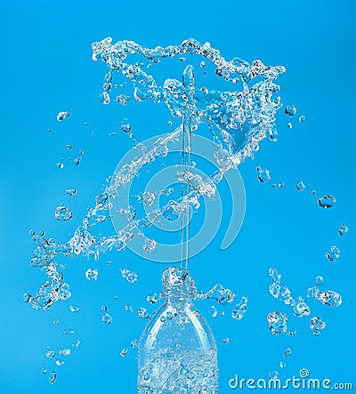 A splash of water with drops escaping from a PET bottle on a blue background. The concept of pure bottled water Stock Photo