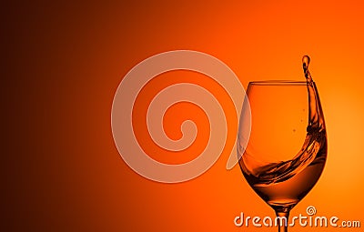 Splash of water in a glass on an orange background Stock Photo