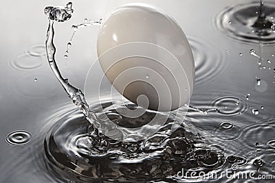 Splashes from an egg bouncing off water surface Stock Photo