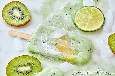 Ice lolly. Sweet melting ice cream with pieces of different fruits, ice and splashes on a gray background. A refreshing Stock Photo