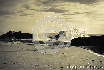 Huge splashing wave of atlantic ocean against blockhouse silhouette in sunset sky in black and white with yellow filter, capbreton Stock Photo