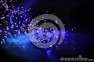 Split debris of purple stone exploding with blue dry river sand against black background Stock Photo