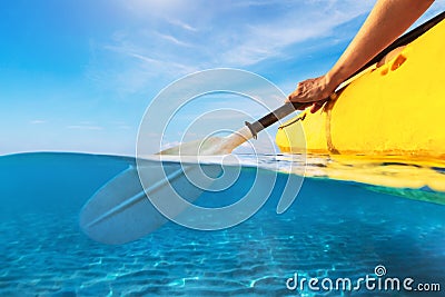 Split view of person kayaking in transparent blue sea, underwater and above water photography of kayak and paddle in warm summer Stock Photo