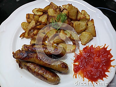 Crispy fried potatoes and pork sausages Stock Photo