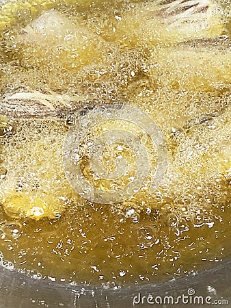 Sponge the boiling oil on the pan. Close-up of fish pieces in old boiling oil with lots of bubbles in a pan of street food in a Stock Photo