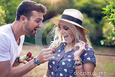 Spontaneous man giving strawberry to his surprised girlfriend Stock Photo