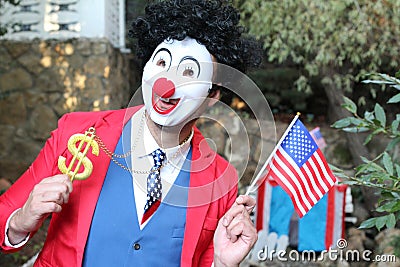 Spooky clown holding flag and dollar sign Stock Photo