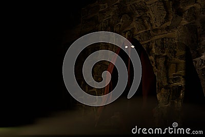3d render of spooky figure with glowing eyes before stone wall Stock Photo