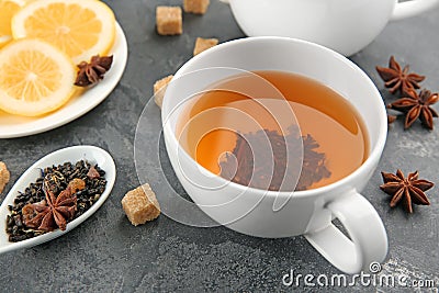 Spoon with dry green tea leaves and cup of aromatic beverage on table Stock Photo