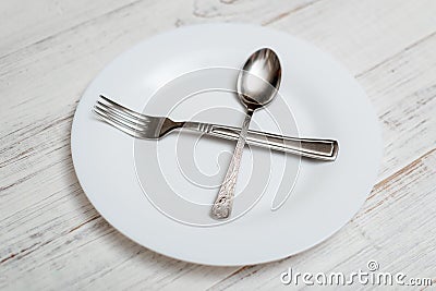 The spoon and fork are on an empty plate. Diet concept, intermittent fasting Stock Photo