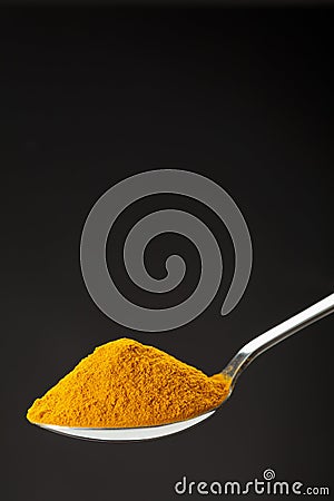 Spoon of ground turmeric on black background Stock Photo