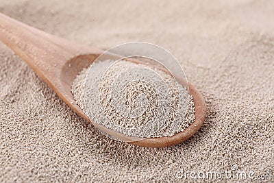 Spoon on pile of active dry yeast, closeup Stock Photo