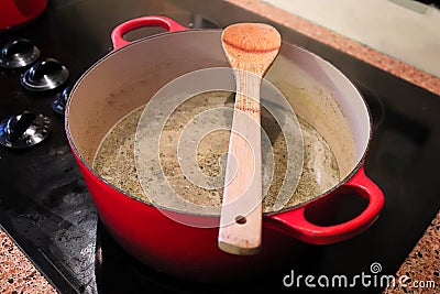 A spoon resting on top of a pot with soup boiling in it Stock Photo