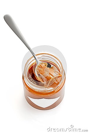 Spoon with salted caramel sauce on jar isolated on white Stock Photo