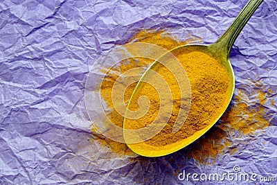 Spoon with turmeric on lilac background Stock Photo