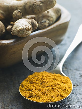 Spoon of Turmeric Powder with fresh Turmeric Root Stock Photo