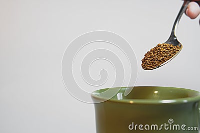 A spoonful of coffee about to pour it into a green cup Stock Photo