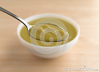Spoonful of green pea soup with bowl in the background Stock Photo